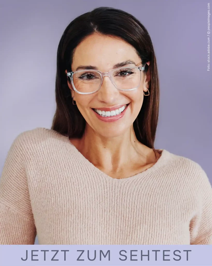 Portrait einer Frau älteren Alters mit Brille und dunklen langen Haaren, die lächelnd in die Kamera schaut